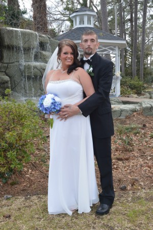 Erin Cooper and Robert Love stand near a waterfall after their gazebo wedding